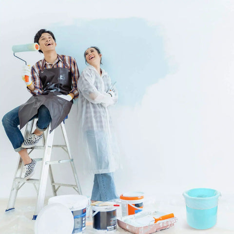 People painting wall with various paint buckets and supplies, near 10 Pcs Paint Filter Strainer Bags White Fine Mesh For 5 Gallon Buckets Elastic Top Disposable Filter Bags For Painting No Mess Staining, Gardening And Plant Protection 250 Micron Mesh, using a paint roller.