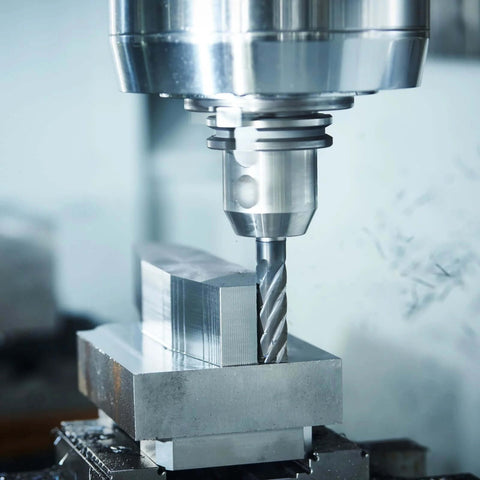 Close-up of a silver 4-flute end mill (3/8 in dia, 3/8 in shank) cutting a metal block in CNC milling.