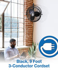 Industrial Grade Wall Mount Fan 20 Inch Black One Sixth Horsepower Three Speed 120 Volt next to man working by window