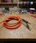 Upgrade Your Ride With Heavy Duty E Bike Motor Extension Cable Featuring Premium Pure Copper Core And High Conductivity For 1000W Systems Designed To Handle Massive Loads Without Voltage Drop While Staying Super Durable And Weatherproof In Any Climate. orange e-bike motor extension cable with copper core and ring terminals on workbench
