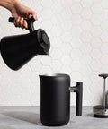 Corvo EKG Pro Electric Tea Kettle With Precise Temperature Control Quick Heat Scheduling And Built In Brew Timer Matte Black With Walnut Handle 0.9 Liter Capacity For Tea Coffee And Cooking pouring water into a mug