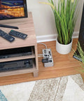 Heavy Duty 6 Outlet Power Strip Surge Protector With 3330 Joules 6 Foot Cord in living room setup on floor by TV stand