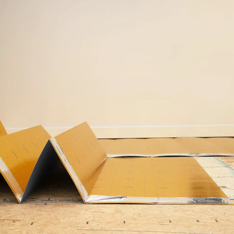Premium Flooring Underlayment Roll 100 Sq Ft 2Mm Thick With PreTaped Sides Fan Fold Grid Cut Design laid out on the floor.