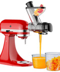 Front view of Cofun masticating juicer attachment for KitchenAid on a red stand mixer; juice streams into a glass with citrus slices