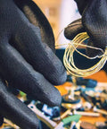 Close-up of hands wearing PUG17 Lightweight Polyurethane Dipped Work Gloves handling wires, showing anti-static grip.