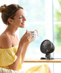 Desktop Mini USB Fan With Stepless Speed Control And Quiet Powerful Airflow Boss Level Cooling on table next to woman.