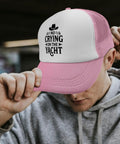 Man wearing pink and white baseball cap with 'No Crying on the Yacht' text indoors