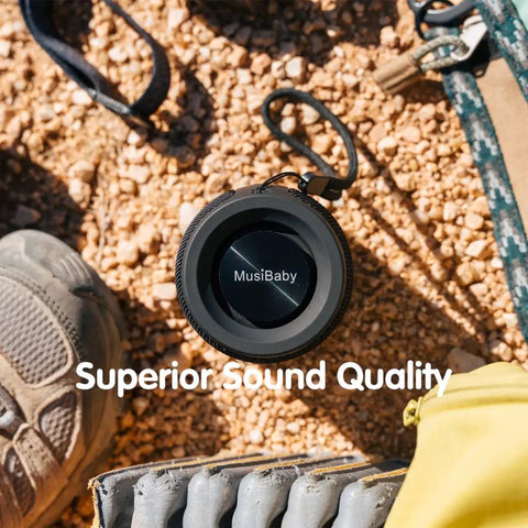 Compact Waterproof Portable Bluetooth Speaker with deep bass on gravel, featuring dual pairing and 24 hour playtime.
