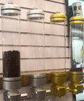 Wall Mounted Coffee Bean Dispenser With Hella Spacious Large Capacity Transparent Acrylic Jar In Slick Gold Finish For Busy Commercial Shops And Top Shelf Home Bars with coffee beans.