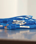Badass Industrial Heat Shrink Labels Half Inch Tube With Black Print On White used for tagging blue Ethernet cables.