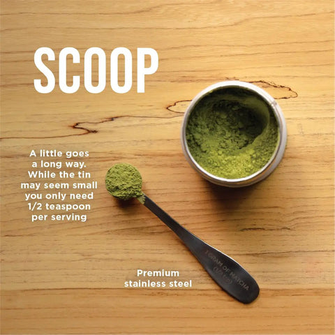 Top view of matcha powder in a tin with a premium stainless steel scoop on a wooden surface