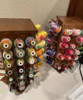 Pretty Slick Wooden 84 Spool Thread Rack With 360 Degree Rotation And Hidden Compartments For Sewing Embroidery Craft Threads Storage Organizer And Needles Bobbins, displaying colorful threads on two wooden racks.
