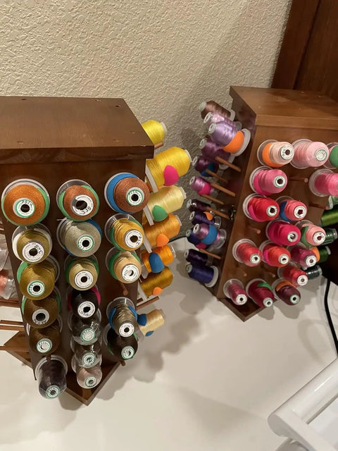 Pretty Slick Wooden 84 Spool Thread Rack With 360 Degree Rotation And Hidden Compartments For Sewing Embroidery Craft Threads Storage Organizer And Needles Bobbins, displaying colorful threads on two wooden racks.