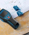 The Real Deal Digital Wall Scanner And Floor Detection Tool Finds Live Wires And Pipes With Dead Nuts Accuracy High Precision Stud Finder on wooden surface with blue accessories.