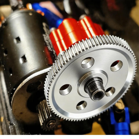 Close-up of a Gen7 Upgrades 45 Hardened Steel Beefy Spur Gear 87T installed on RC car motor, showing silver finish and gear teeth.