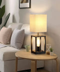 Two Bulb Farmhouse Bedside Lamp With USB Ports And AC Outlet Cozy Beige Fabric Shade Table Light For Bedroom Living Room Bulbs Included Ideal For Reading And Relaxing on side table next to a sofa
