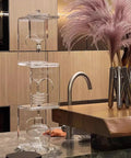Topnotch Cold Brew Coffee Maker With Slow Drip Ice Tank And Large Capacity Glass Carafe On Solid Wood Base in a modern kitchen setting.