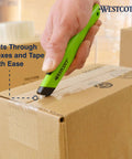 Westcott safety ceramic box cutter with green handle cutting a cardboard box (close-up view)