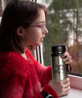 Person holding Insulated Water Bottle For On The Go Hydration 800ml Stainless Steel Flask with black cap by a window