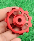 Close-up of a red 2 Pack 11T Aluminum Sealed Bearing Jockey Wheel Rear Derailleur Pulley For Bike on green grass
