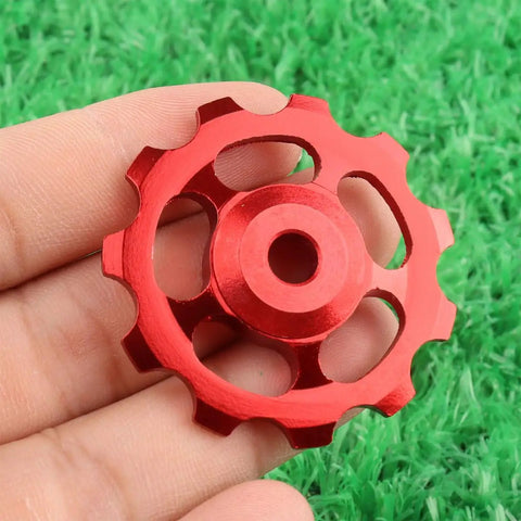 Close-up of a red 2 Pack 11T Aluminum Sealed Bearing Jockey Wheel Rear Derailleur Pulley For Bike on green grass