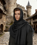 Man in black cloak with castle backdrop, representing Epic Seven Piece Renaissance Costume Set For Men With Faux Leather Pauldron