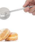 Hand holding Flour Duster For Baking One Handed Operation Stainless Steel Powdered Sugar Shaker over donuts