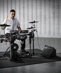 Musician playing electronic drums with 35-Watt Drum Amplifier With Dual 8-Inch Speakers For Jam Sessions nearby
