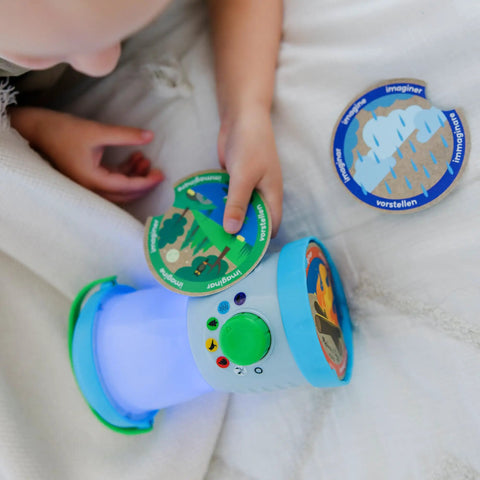 Child playing with Durable Light And Sound Camping Lantern Toy With Six Color Modes and scene cards on a bed.