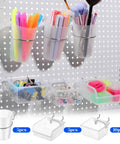 20 Piece Pegboard Organizer Set With Bins Cups Hooks And Loops For Garage Workshop Workbench And Office Pro Grade Clear Pegboard Storage System with pens, markers, and small items displayed in bins and cups on a pegboard.