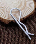 Single M3 60mm cotter pin from 20Pcs M3 60mm Cotter Pins R Clips Hairpin Assortment Kit for trailer hitch lock systems on wood surface.
