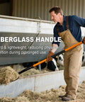 Man using 5 Tine Pitchfork For Gardening Heavy Duty With Fiberglass Handle Garden Fork For Mulching And Hauling Debris indoors.