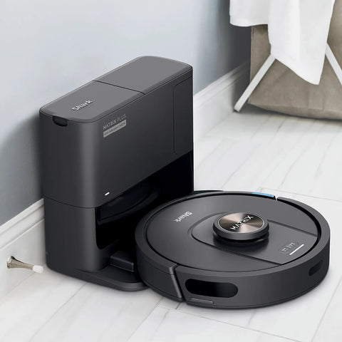 Robot Vacuum With Matrix Clean And Precision Mapping Self Empty Base With 30 Day Capacity Bagless Powerful Pet Hair Cleaning WiFi Enabled Black Renewed on charging dock in bathroom with gray and white interior.