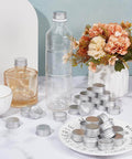 36 Pack Silver Aluminum Seal Screw Caps for Round Steel Tins with Plastisol PE Liner, 30mm/1.2in x 13mm/0.5in Thick, Fits 27mm/1.1in Inner Diameter, Airtight Leakproof Kitchen Home displayed on a marble surface surrounded by bottles and flowers.