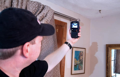 Person using MR160 Imaging Moisture Meter with IGM Tech, Thermal Imaging, Pin And Pinless Detection, 80x60 Resolution indoors.