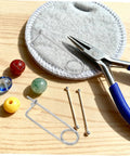 Heavy Duty Stainless Steel Brooch Cotter Safety Spring Pins For Quick Lock with beads and pliers on a wooden surface.