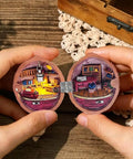 Hands holding a miniature dollhouse scene in a round wooden box, featuring tiny furniture and decor, showcasing 100 Pcs Tiny Dollhouse Hinges 0.7 x 0.51 Inches 180 Degree Miniature Metal Hinges With 400 Screws Silver Durable Iron Hardware for Wooden Boxes Cabinets Dollhouse Furniture Craft.