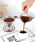 Hand pouring coffee into cup with Pour Over Coffee Dripper With Stainless Steel Filter Reusable Paperless Cone Dripper in background