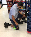 Worker wearing Ultra Soft Knee Pads For All Day Comfort Large Fluorescent Green With Adjustable Straps in a store aisle