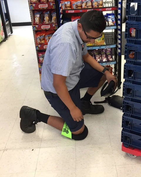 Worker wearing Ultra Soft Knee Pads For All Day Comfort Large Fluorescent Green With Adjustable Straps in a store aisle