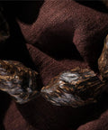 Close-up of Vietnam Nha Trang Agarwood Unisex Jewelry Burl Scarred Black Oil Aged Raw Material on fabric background.