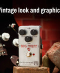 Ram's Head Big Muff Pi Fuzz Pedal With True Bypass And Battery Included, Vintage Look And Graphics on brick surface beside guitar
