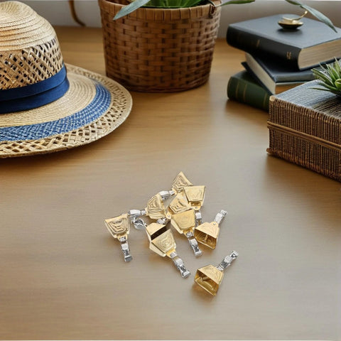 Front view of gold and silver stainless steel clip-on fishing bite alarm bells; 15-piece set on a wooden surface.