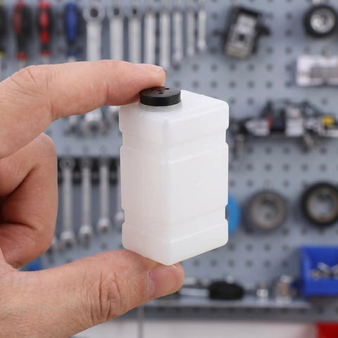 Clear 120CC RC Plane Fuel Tank Set With Metal Tubing And Engine Container held in hand, showcasing compact size.