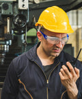 100 Pack Bulk Safety Glasses Featuring Bully Proof Polycarbonate Lenses And Heavy Duty Scratch Protection For Job Sites And Weekend Rigs Rainbow Mix Set worn by a worker with a yellow hard hat.