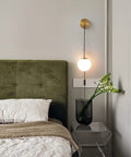 Set Of Two Brushed Gold Plug In Wall Sconces With White Glass Globe Shades Dope Modern Indoor Wall Lights next to a bed