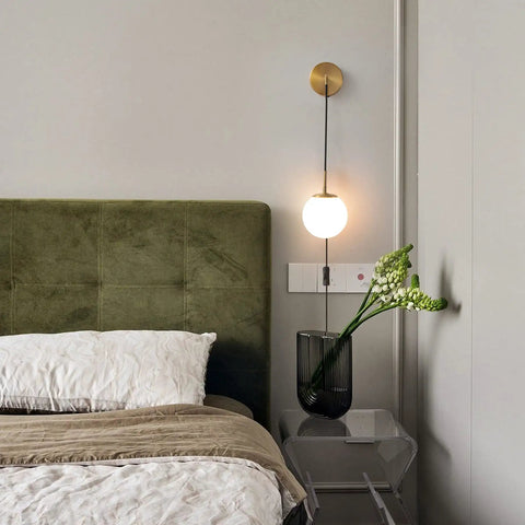 Set Of Two Brushed Gold Plug In Wall Sconces With White Glass Globe Shades Dope Modern Indoor Wall Lights next to a bed