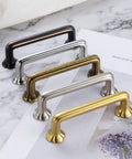 Assorted cabinet pull handles in various finishes on a marble surface, including oil rubbed bronze with clover design, front view.