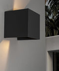 Front view of a black rectangular metal outdoor wall light mounted on a gray exterior wall.