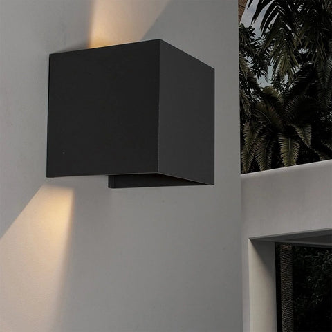 Front view of a black rectangular metal outdoor wall light mounted on a gray exterior wall.